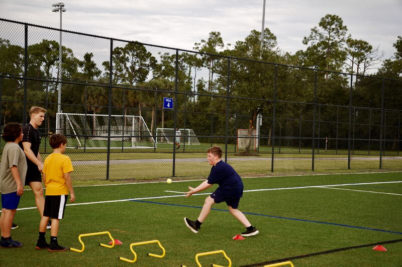 Athlete fielding a ball while teammates and the coach look on